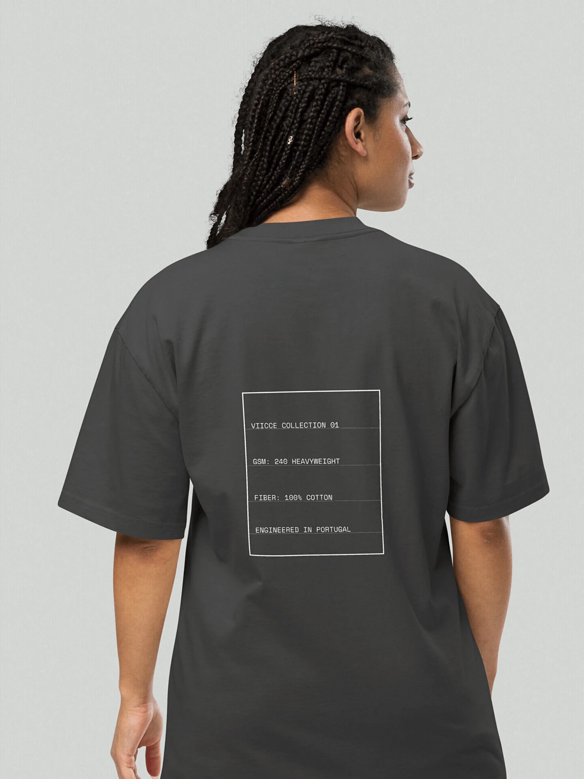 Rear view of a person wearing the VIICCE dark grey oversized faded t-shirt featuring a white minimalist technical spec box print on the back.