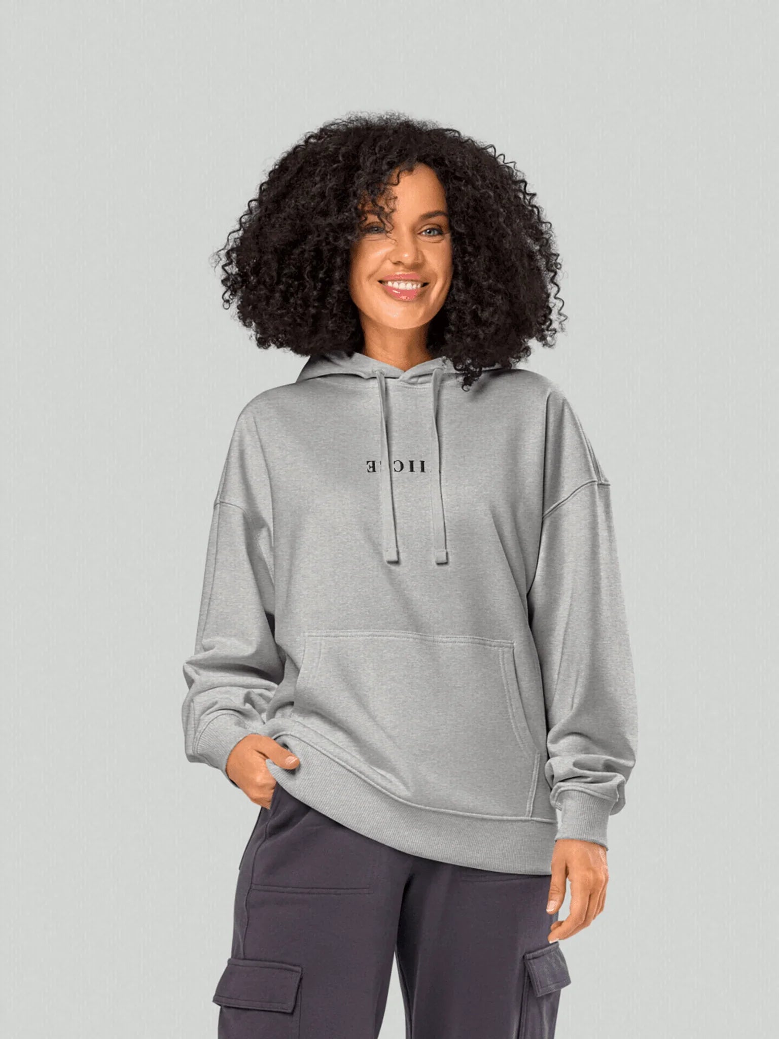 VIICCE Core Heavyweight Hoodie in Concrete Gray. Women's model with Viicce written upside down on the chest. Minimalist streetwear style. Studio photo.