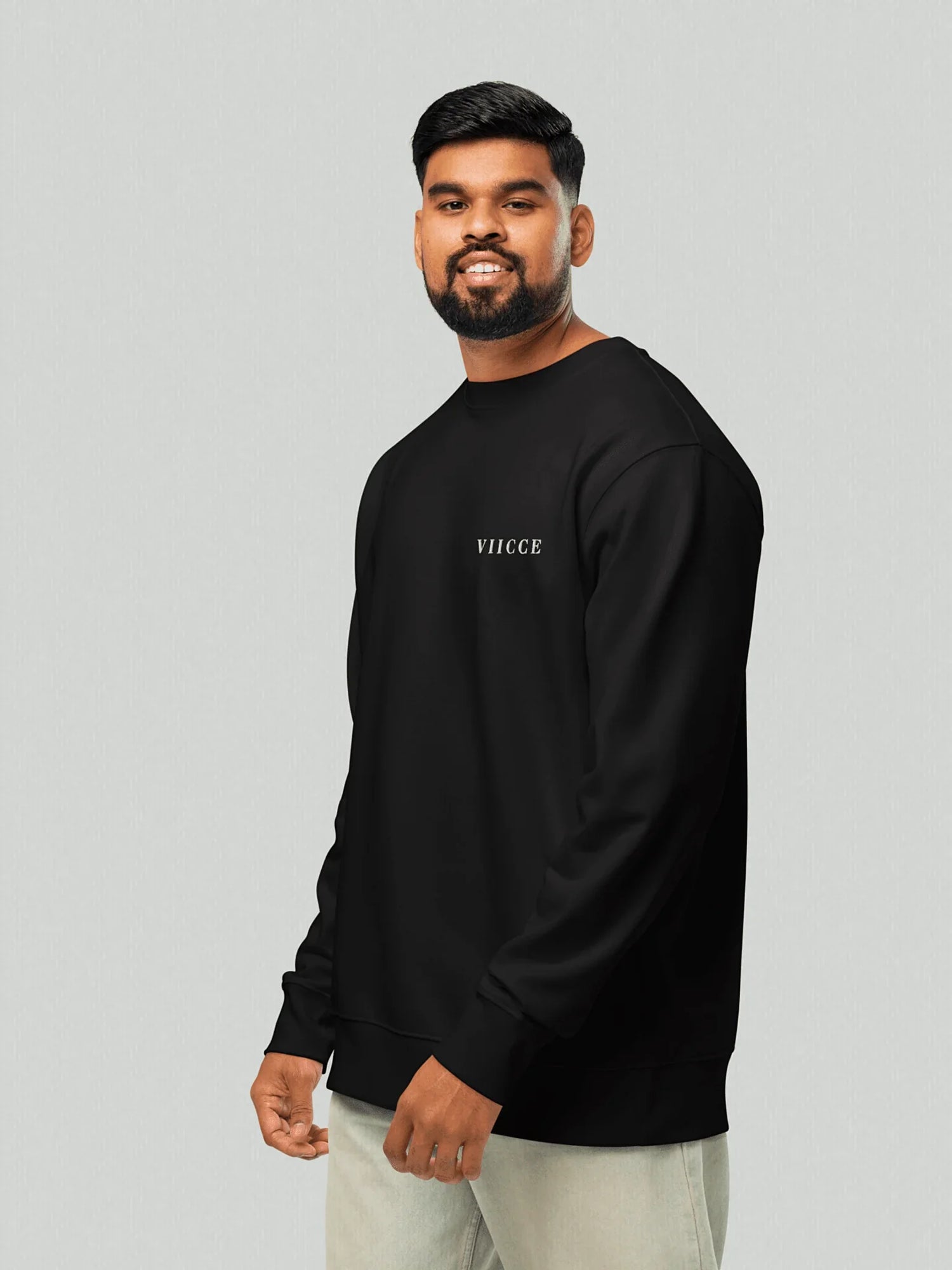 Male model wearing the Core Heavyweight Sweatshirt | Jet Black. The 3/4 sleeve style highlights the relaxed fit in the arms and the discreet VIICCE logo on the chest. Essential and sustainable streetwear style.