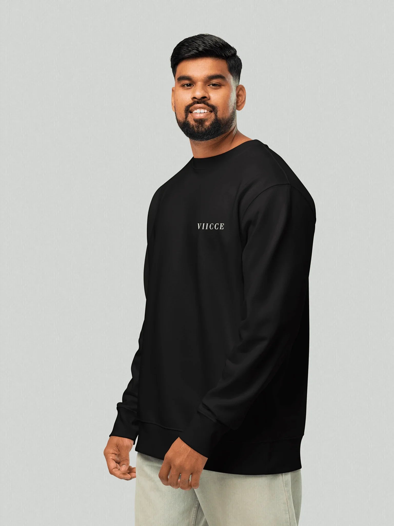 Male model wearing the Core Heavyweight Sweatshirt | Jet Black. The 3/4 sleeve style highlights the relaxed fit in the arms and the discreet VIICCE logo on the chest. Essential and sustainable streetwear style.
