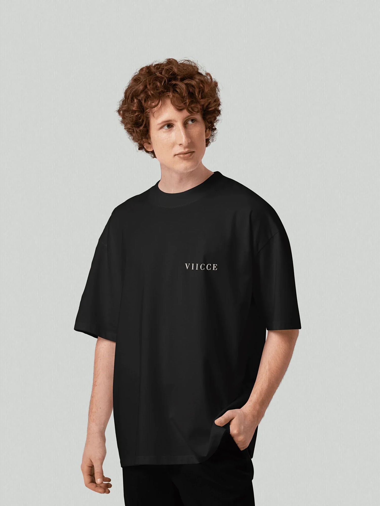 Essence Tee - Pure Black. Men's boxy, oversized t-shirt with a chevron print on the left chest. Made from high-quality, heavyweight organic cotton. Studio photo.