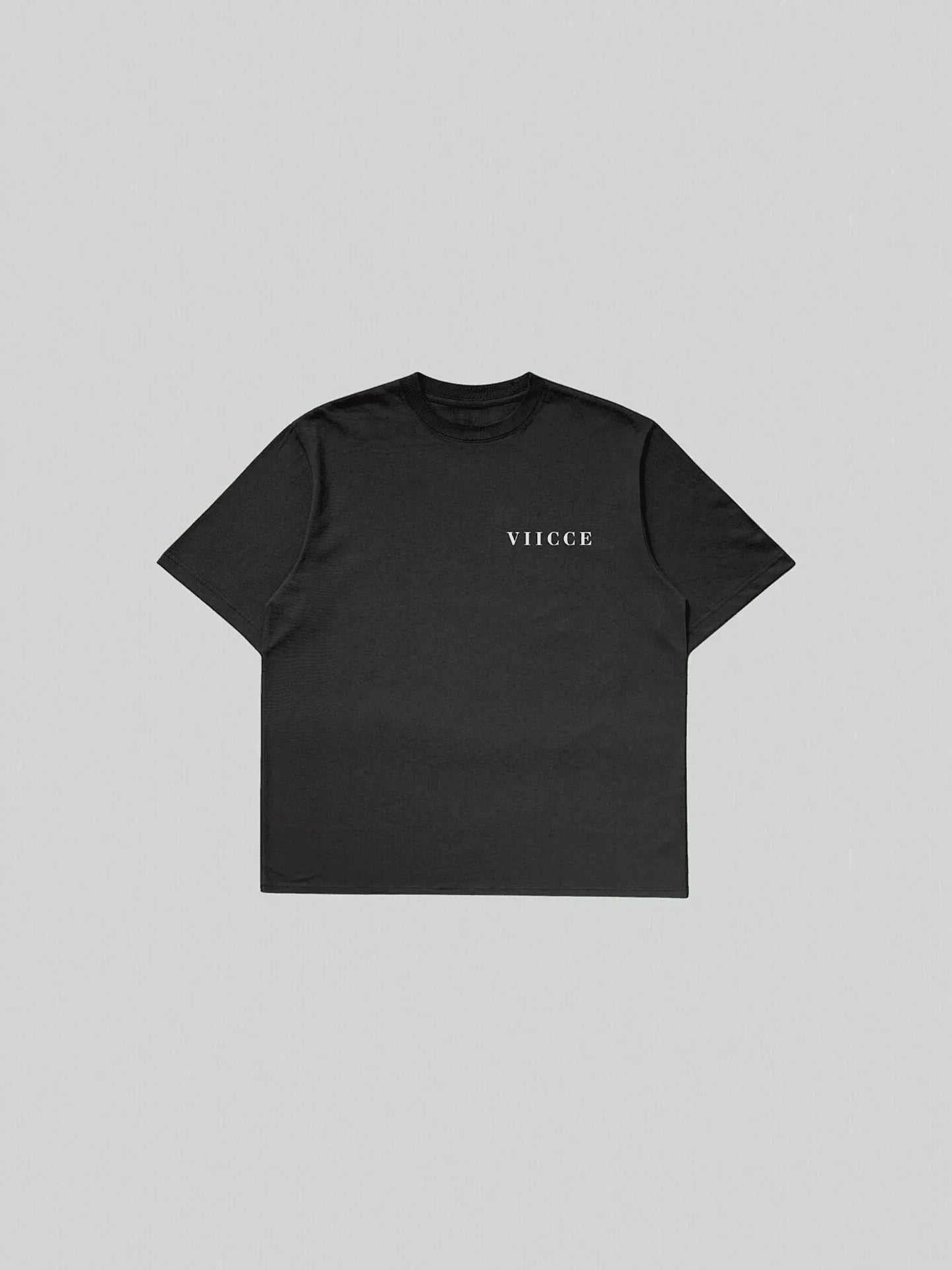 Essence Tee - Pure Black. T-shirt laid flat on the floor with "viicce" written on the left side of the chest. Made with high-quality, heavyweight organic cotton. Studio photo.