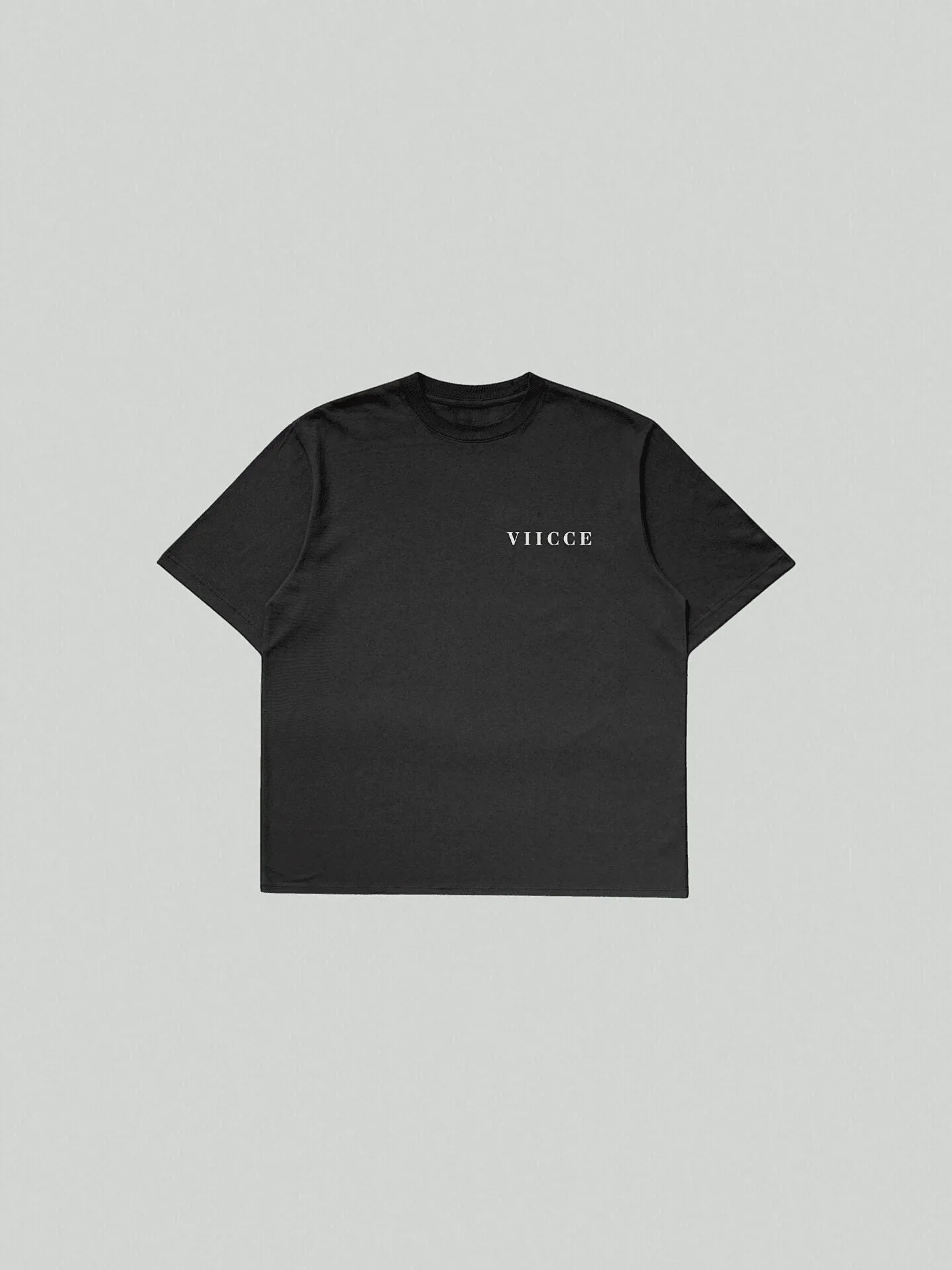 Essence Tee - Pure Black. T-shirt laid flat on the floor with "viicce" written on the left side of the chest. Made with high-quality, heavyweight organic cotton. Studio photo.