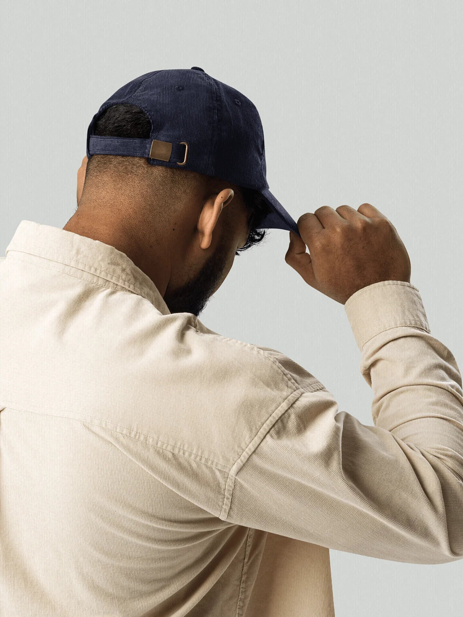 Male model wearing a blue VIICCE corduroy cap and beige shirt, seen from behind